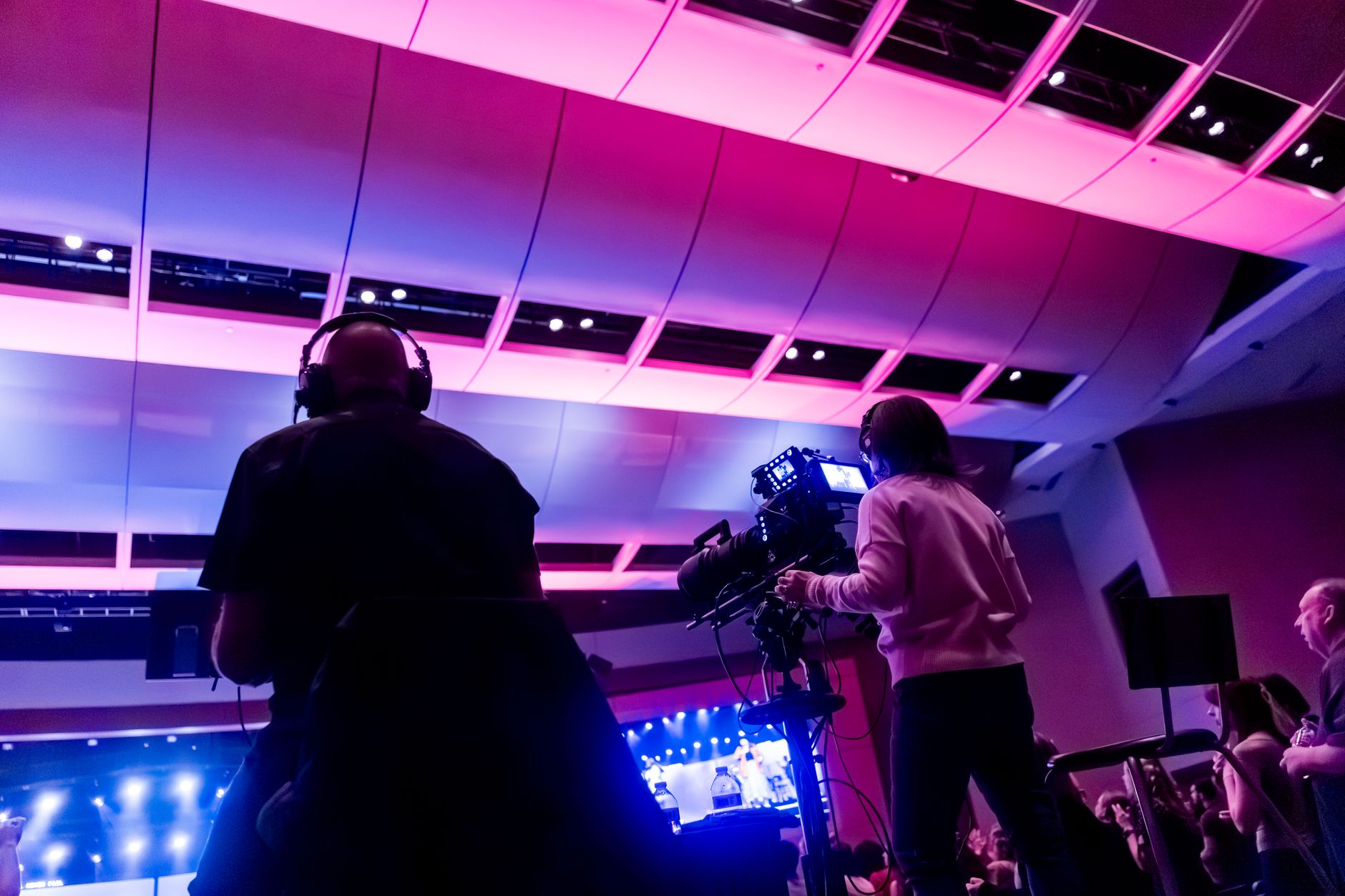 A camera crew filming a live event under stage lighting