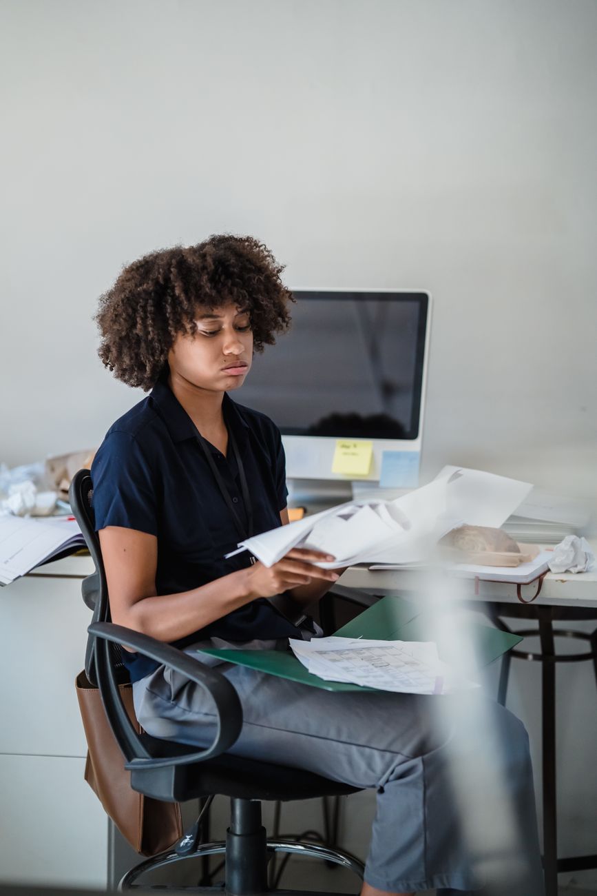 A woman reading documents at a desk in an office
